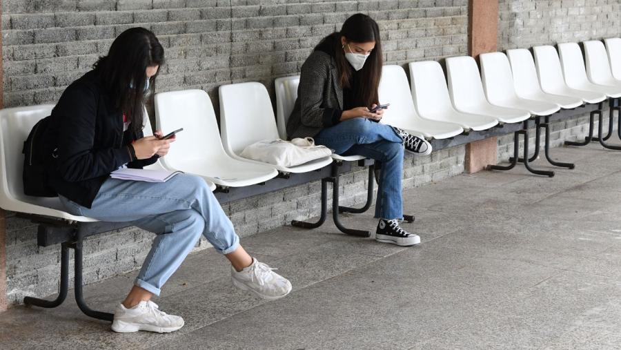 Dúas estudantes consultan os seus móbiles nun espazo universitario Dúas estudantes consultan os seus móbiles nun espazo universitario